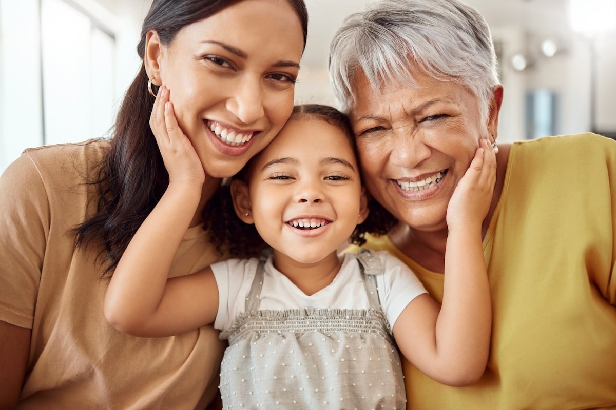 Three people smiling closely together, including a child and two adults.