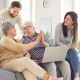 A family of four happily interacting in a living room